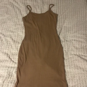 Beige ribbad klänning - Säljer en superfin beige ribbad klänning med smala axelband. Perfekt för sommardagar eller en avslappnad kväll. Klänningen är i ett mjukt och stretchigt material som ger en bekväm passform. Passar både till vardags och festliga tillfällen!