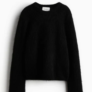 Svart fluffig tröja från H&M - Mysig svart tröja från H&M i mohair mix material. Perfekt för kyliga dagar med sin varma och bekväma känsla. Tröjan har en enkel design med långa ärmar
