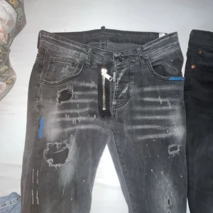 Disquerd2 black jeans - Säljer ett par grå jeans med coola slitningar och en unik dragkedja på framsidan. De har en modern look med en lite sliten stil, perfekt för en avslappnad outfit. Passar bra till både vardag och fest!