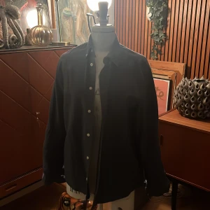 Mörkblå skjorta från H&M - Säljer en stilren mörkblå skjorta från H&M i storlek S. Skjortan har en klassisk design med knappar framtill och långa ärmar. Perfekt för både vardag och festliga tillfällen. Materialet känns bekvämt och passar bra till olika outfits. Ett måste i garderoben! 💙