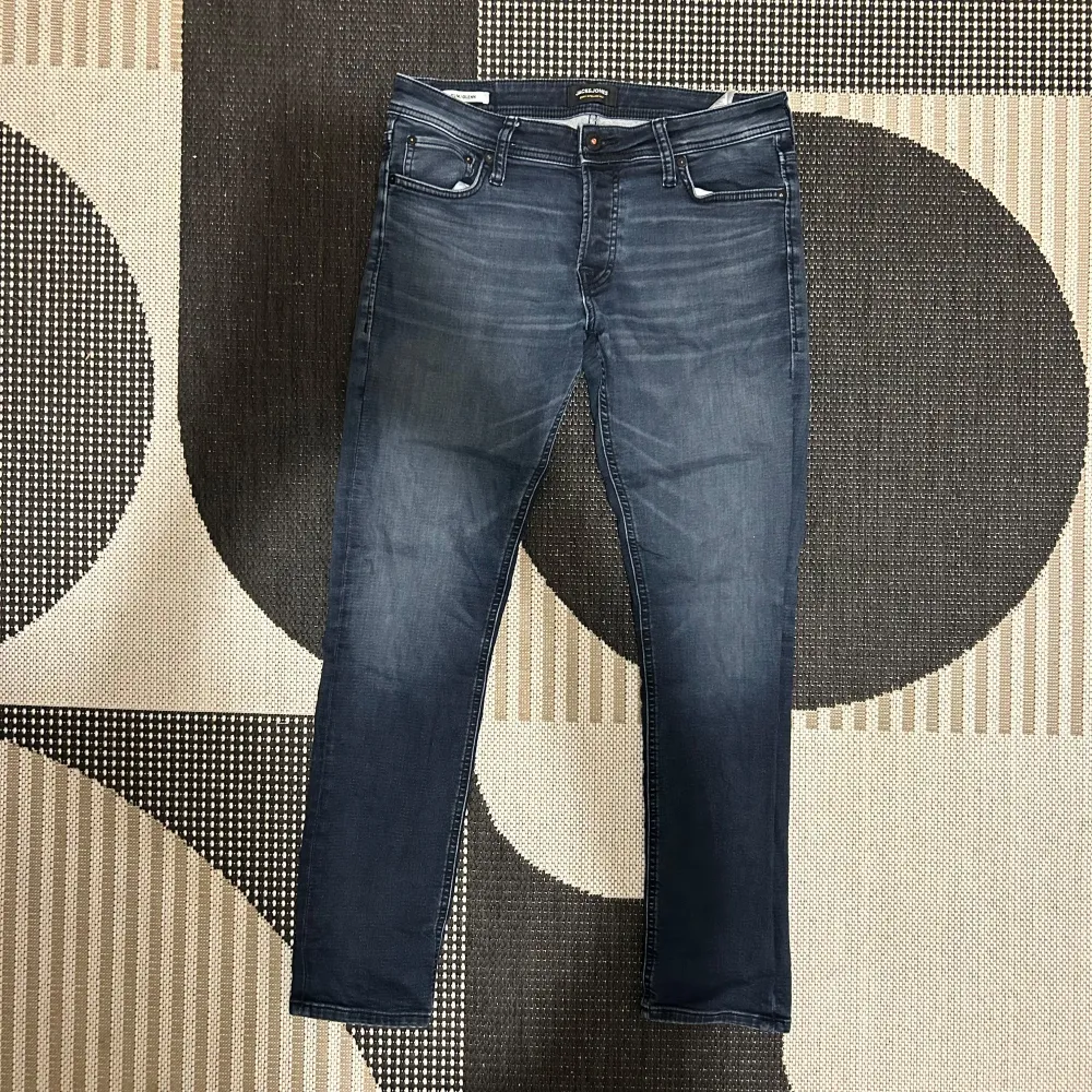 Säljer ett par snygga mörkblå slim jeans från Jack & Jones i modellen Glenn. De är i bra skick och perfekta för både vardag och fest. Jeansen har en klassisk femficksdesign och är tillverkade i ett stretchigt material för extra komfort. Passar perfekt till en t-shirt eller skjorta!. Jeans & Byxor.