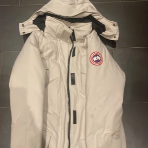 Canada goose jacka - Säljer en snygg beige dunjacka från Canada Goose i storlek M. Jackan har en praktisk huva och dragkedja framtill. Perfekt för kalla vinterdagar. Den är i mycket bra skick och redo för nya äventyr!KAN OCHSÅ TÄNKA MOG ATT BYTA 💕💕💕🙌🙌🙌🙌🙌🙌