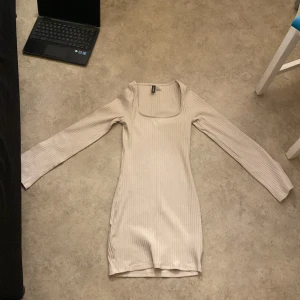 Beige ribbad klänning från H&M Divided - Säljer en superfin beige ribbad klänning från H&M Divided i storlek S. Klänningen har en tight passform och långa ärmar, perfekt för både vardag och fest. Den är i mycket bra skick och passar perfekt till höst och vår. Enkelt att styla med både sneakers och klackar!