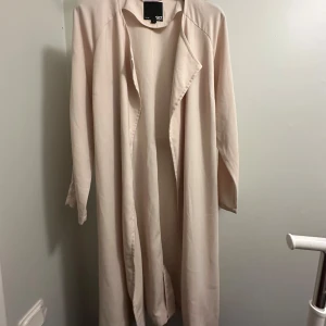 Beige trenchcoat  - Säljer en stilren beige trenchcoat från 157 i storlek L. Den har långa ärmar och ett bälte i midjan för en snygg passform. Perfekt för vår och höst! Den är helt oanvänd! 