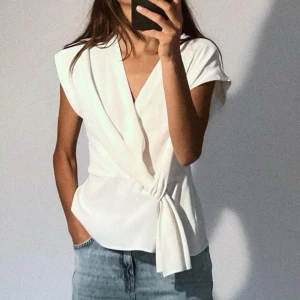 Zara blus! - Snygg vit omlottblus med knytning i sidan. Perfekt för både vardag och fest. Den har en elegant v-ringad design och är ärmlös🩷🩷xs är helt SLUTSÅLD så passa på o köp!!