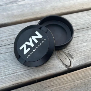 Snusdosa i metal - Zyn - Helt nytt & oanvänt  Uppgradera din snusupplevelse med vår exklusiva svarta snusdosa i metall med två praktiska fack. Denna sofistikerade dosa har inte bara en stilren design, utan den är också lasergraverad med ett unikt och elegant "ZYN"-motiv som 