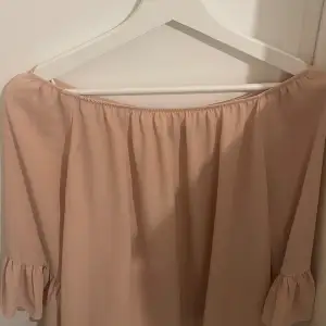 Säljer en superfin beige off-shoulder topp från BikBok. Den har en lös passform och är tillverkad i ett mjukt och skönt material. Toppen har korta ärmar med volangdetaljer som ger en söt touch. Perfekt för sommaren eller en festlig kväll!