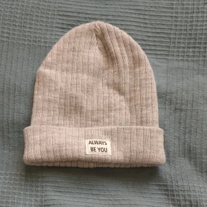 Grå ribbad mössa med text - Säljer en snygg grå ribbad mössa med texten "Always be you" på framsidan. Mössan passar någon med litet huvud då den är en barnmössa. Perfekt för höst och vinter. Skriv gärna till mig om du har fler frågor!