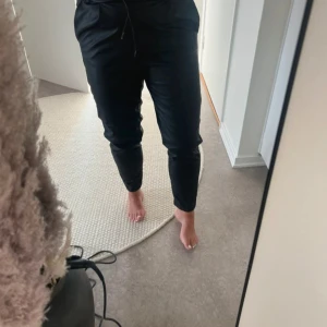 Svarta mjukisbyxor med snörning - Säljer ett par svarta skinbyxor med snörning i midjan. Byxorna är bekväma och perfekta för fin middag eller fest. De har en normal passform.