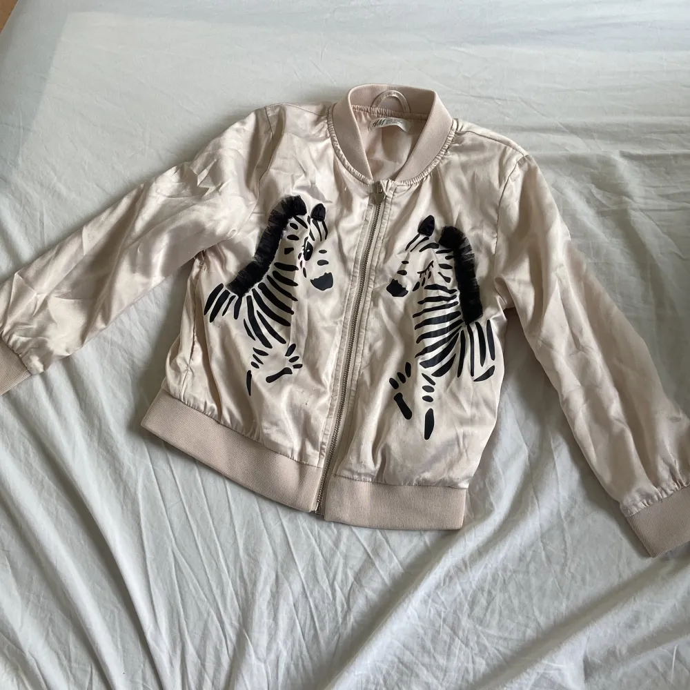 Säljer en superfin beige bomberjacka från H&M i storlek EUR 116 (5-6 år). Jackan har ett coolt zebramönster på framsidan och en dragkedja. Perfekt för vår och höst! 🦓. Jackor.