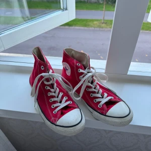 Röda Converse All Star sneakers - Säljer ett par klassiska röda Converse All Star sneakers i storlek 39. Skorna är i bra skick med vita snören och den ikoniska vita gummisulan. Perfekta för både vardag och fest!