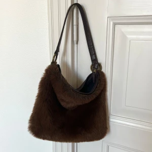 Brun pälsväska med skinnrem - Väska med päls på utsidan och skinn på baksidan. Har en skinnrem och stängs med dragkedja. Perfekt för höst och vinter! 👜✨