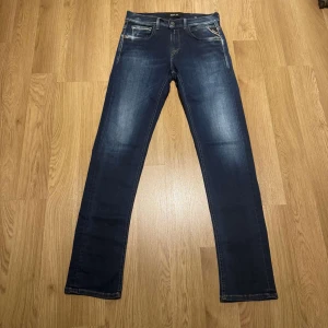 Mörkblå jeans från Replay - Snygga mörkblå jeans från Replay med en klassisk femficksdesign och diskreta slitningar. De har en knappgylf och en läderpatch med Replay-logga baktill. Perfekta för en stilren look.