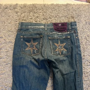 Blå jeans med stjärndetaljer - Snygga blå jeans med broderade stjärnor på bakfickorna. De är från Victoria Beckham från början. Jag har sytt om dem till mer utsvängda då d från början bara var lite💗midjemåttet är 72 och d är Lågmidjade 