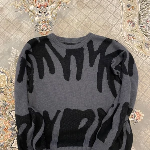 Grå och svart mönstrad tröja - Säljer en cool grå tröja med svart abstrakt mönster. Tröjan har en rund hals och långa ärmar, perfekt för en stilren look. Passar bra till både jeans och chinos.