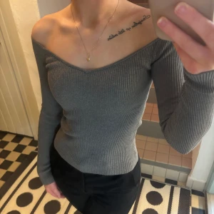 Grå ribbad offshoulder-tröja - Snygg grå ribbad tröja med offshoulder-design och långa ärmar. Perfekt för en stilren look.