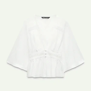 Vit blus från Zara - Säljer en elegant vit blus från Zara med v-ringning och spetsdetaljer. Perfekt för en stilren look. Knappen längst ned går inte att knäppa då bandet för knappen lossnat men går lätt att sy på ett nytt vitt band. Helt slutsåld på hemsidan. Kan byta mot en i M.