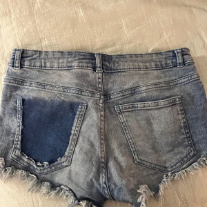 Blå jeansshorts med fransar - Super snygga blå jeansshorts från HM med fransiga kanter och klassisk femficksdesign. Perfekta för en avslappnad sommarlook💗