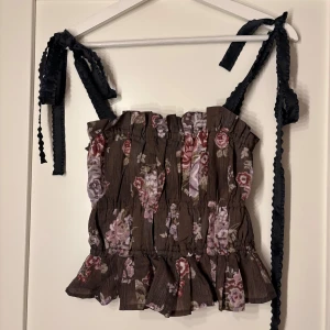 Blommig topp med volangdetaljer  - Säljer en söt blommig topp från H&M med volangdetaljer och super gulliga knytband på axlarna. Perfekt för en somrig look!! 🌼Har aldrig använts ✨