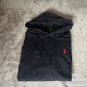 Ralph Lauren hoodie - Säljer en stilren svart hoodie från Ralph Lauren med en röd broderad logga på bröstet. Tröjan har en klassisk design med huva. Perfekt för en avslappnad look. Priset sitter som berget⛰️