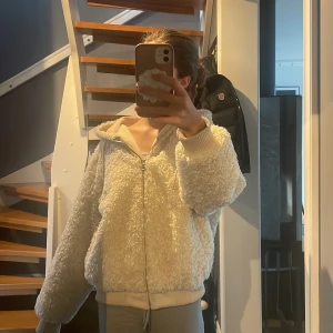 Vit teddyjacka från Zara - Mysig vit teddyjacka från Zara med dragkedja och huva. Jackan har en loose passform och ribbade muddar vid ärmslut och nederkant. Nästan helt ny och kostade 799