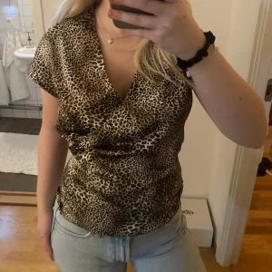 Leopardmönstrad omlottopp - Säljer en snygg leopardmönstrad omlottopp med korta ärmar. Passar S-M