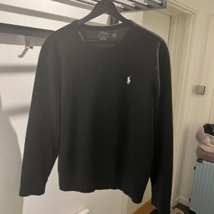 Svart tröja från Polo Ralph Lauren M - Säljer en stilren svart tröja från Polo Ralph Lauren med det klassiska broderade logotypen på bröstet. Tröjan har långa ärmar och är tillverkad i ett mjukt material för extra komfort. Perfekt för en avslappnad look.