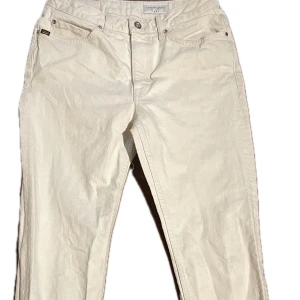 Beige byxor från Tiger of Sweden - Snygga beige byxor från Tiger of Sweden i modellen MEG. Byxorna har en klassisk design med dragkedja och knappar. Perfekta för en stilren look.