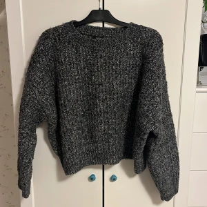 Grå stickad tröja från Lindex - Mysig grå stickad tröja från Lindex. Perfekt för kyliga dagar med sin varma och bekväma design. Tröjan har långa ärmar och en klassisk rund halsringning.