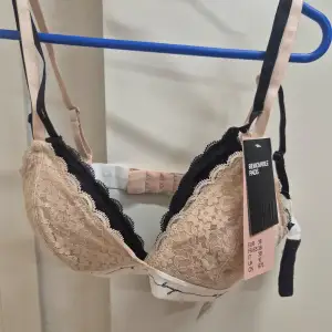 Beige och svart spets-bh från H&M med avtagbara vadderingar. Den har justerbara axelband och en elegant svart spetskant. Helt ny, aldrig använd. 