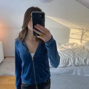 Blå velourjacka med dragkedja - Snygg blå velourjacka med dragkedja framtill. Jackan har en normal passform och långa ärmar, perfekt för en avslappnad stil. Den mjuka velouren ger en lyxig känsla. Tröjan har en polokrage som man antingen kan ha mer öppet eller uppdragen.🩷