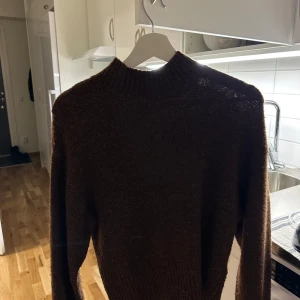 Svart stickad tröja - Mysig svart stickad tröja med hög krage. Perfekt för kyliga dagar och ger en stilren look. Passar bra till både jeans och kjol.