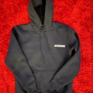 Svart hoodie från Jacquemus - Snygg svart hoodie från Jacquemus med justerbar huva och känguruficka. Perfekt för en stilren och bekväm look.