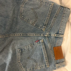 Levi's Ribcage Straight Jeans - Snygga ljusblå Levi's Ribcage Straight jeans med hög midja. Klassisk femficksdesign och ikonisk Levi's-lapp baktill. Perfekta för en avslappnad stil med en modern twist.