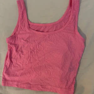 Rosa ribbad linnetopp från Shein - Säljer en söt rosa ribbad linnetopp från Shein. Perfekt för varma sommardagar med sin ärmlösa design och mjuka material. Toppen har en enkel och stilren look som passar till många olika outfits. Säljer toppen för 50kr🥰och är använd 1 gång.