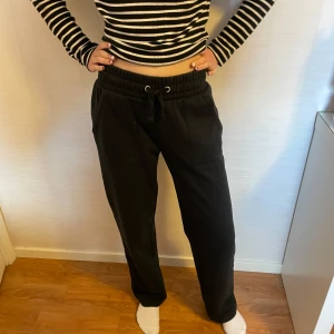 Svarta mjukisbyxor med snörning - Från lager 157🖤 Sweatpants ”Stella low waist” Säljer ett par svarta mjukisbyxor med snörning i midjan. Använd & lite nopprig men i bra skick. Jag är 170cm lång. Byxorna har en loose passform och är perfekta för en avslappnad stil. De är tillverkade i ett mjukt material som ger hög komfort. Fickor både fram & bak😊