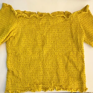 Off-shoulder topp - En fin, stretchig off-shoulder topp från H&M inköpt 2021! Den saknar lapp i bak, men har kvar tvättrådslappen. Den blev en annan gul (än den var från början) i tvätten när den råkade följa med mörka plagg, men är fortfarande superfin! Passar XL också :) 