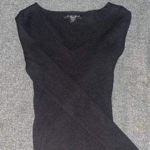 Svart ribbad tröja från Amisu - Snygg svart ribbad tröja från Amisu med vringning. Tröjan har långa ärmar och en figurnära passform.