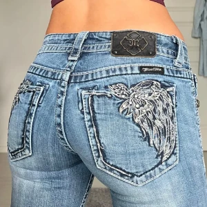 Blå bootcut jeans med broderi - Snygga blå bootcut jeans från Miss Me med unikt broderi på bakfickorna. Jeansen har låg midja och en klassisk femficksdesign.