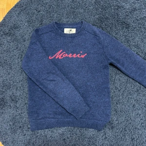 Blå tröja från Morris - Säljer en snygg blå tröja från Morris med röd broderad text på bröstet. Perfekt för kyligare dagar!                                                  Killen på bilden är 172 och väger 55kg.  Tveka inte på att höra av er om ni har några frågor! //Victor ✌️❤️