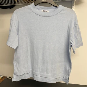 Ljusblå t-shirt från Uniqlo - Säljer en ljusblå t-shirt från Uniqlo. Den har en klassisk design med korta ärmar och rund hals. Perfekt för en avslappnad look.