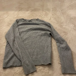 Grå stickad tröja från Vero Moda - Mysig grå stickad tröja från Vero Moda. Perfekt för kyliga dagar med sin ribbade krage och muddar. Enkel och stilren design som passar till det mesta. 🩶