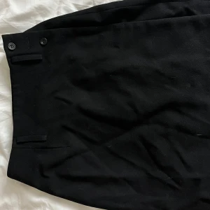 Svart kjol från Mulberry - Elegant svart kjol från Mulberry med knappar i midjan. Väldigt stilren och mycket bra kvalitet i 100% ull. Jättefint skick förutom att en knapp saknas, dock inget som påverkar användningen. Inuti strl 8 men passar mig som vanligtvis har XS🖤
