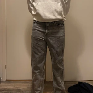 Grå jeans från H&M - Säljer ett par grå loose fit jeans från H&M. De har en klassisk femficksdesign och är perfekta för en avslappnad stil. Tillverkade i ett slitstarkt material som ger en bekväm passform.