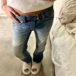Lågmidjade disel jeans - Säljer ett par blå disel jeans med slitningar och låg midja. De har en klassisk femficksdesign och en avslappnad passform. Perfekta för en casual look.