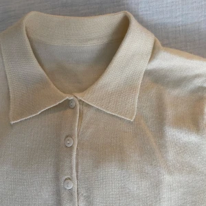 Beige pikétröja - Retro beige pikétröja med långa ärmar och knappar framtill. 