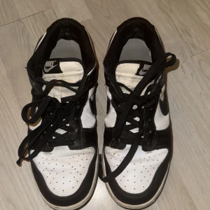 Svartvita Nike sneakers - Air Jordan Low - Snygga svartvita Nike sneakers med klassisk design. Skorna har snörning och en bekväm passform, perfekt för vardagsbruk. Den ikoniska Nike-loggan syns tydligt på sidan och hälen.