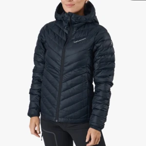 Svart dunjacka från Peak Performance - Snygg och funktionell svart dunjacka från Peak Performance med huva och dragkedja. Jackan har ett quiltat mönster och är perfekt för kyliga dagar. Den är långärmad och har en figurnära passform. Nypris 2800kr 