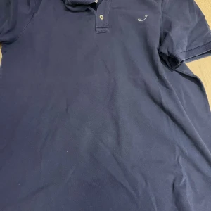 Mörkblå pikétröja från Jacob Cohën - Snygg mörkblå pikétröja från Jacob Cohën med klassisk krage och knappar. Perfekt för en stilren look. Diskret logga på bröstet.