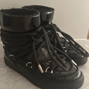 Svarta blanka inuikii boots med snörning - Snygga svarta inuikii boots i blankt material. Använda en säsong men har mycket kvar att ge! Dyra vid inköp storlek 36 ♥️pris kan absolut diskuteras!! 